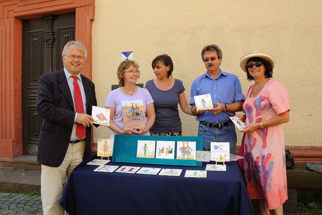 Infostand der Initiative Opferdenkmal e. V. beim „Sommer in der Strackgasse“. Bürgermeister Hans-Georg Brum (links) und der KSfO-Geschäftsführer Udo Keidel-George (Zweiter v.r.) nutzen die Gelegenheit, sich unter den zahlreichen Motiven einige auszusuchen. (Foto: Uwe Seemann) Infostand der Initiative Opferdenkmal e. V.